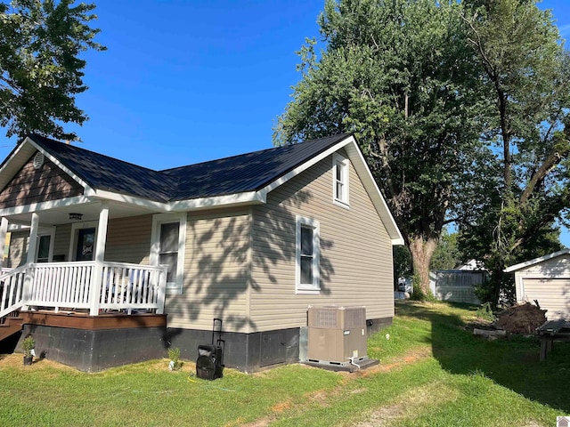 view of property exterior featuring a lawn, covered porch, and central air condition unit