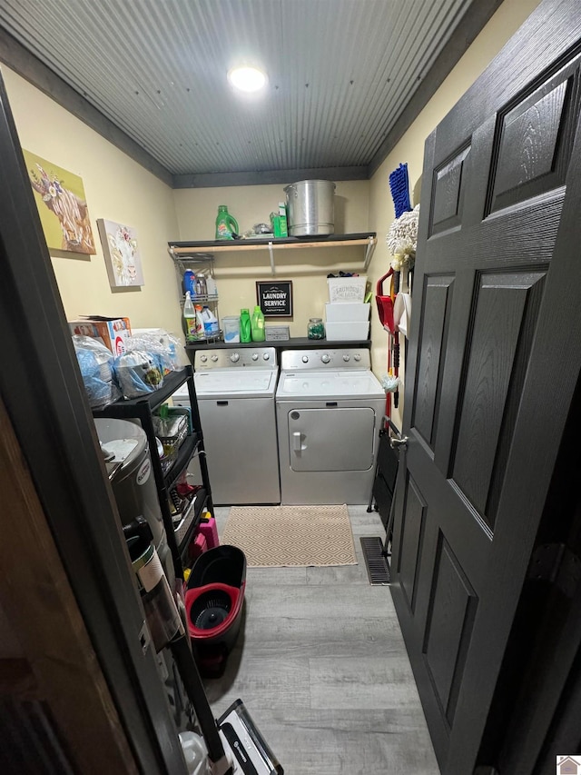 clothes washing area with light wood-type flooring and washer and clothes dryer