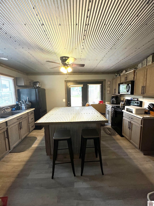 kitchen with sink, black appliances, light wood-type flooring, and a wealth of natural light