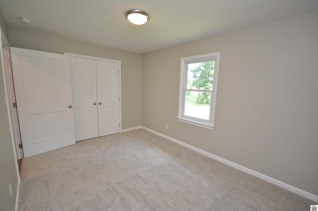 unfurnished bedroom with a closet and light carpet