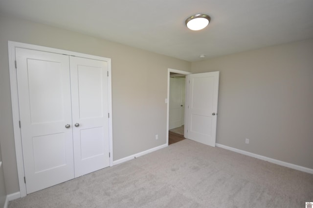 unfurnished bedroom with light carpet and a closet