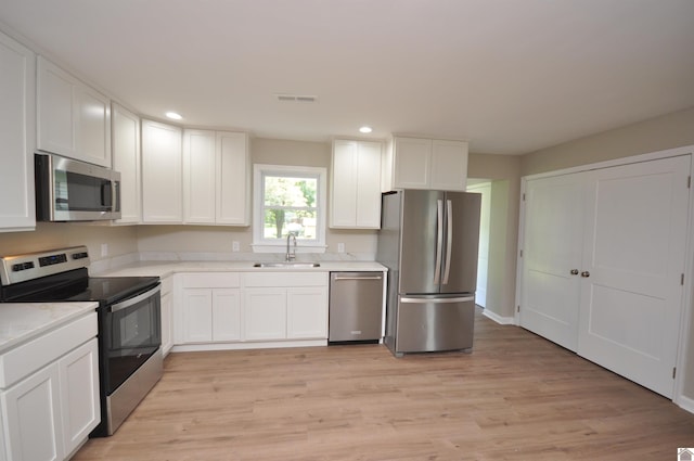 kitchen featuring stainless steel appliances, white cabinetry, sink, and light hardwood / wood-style flooring