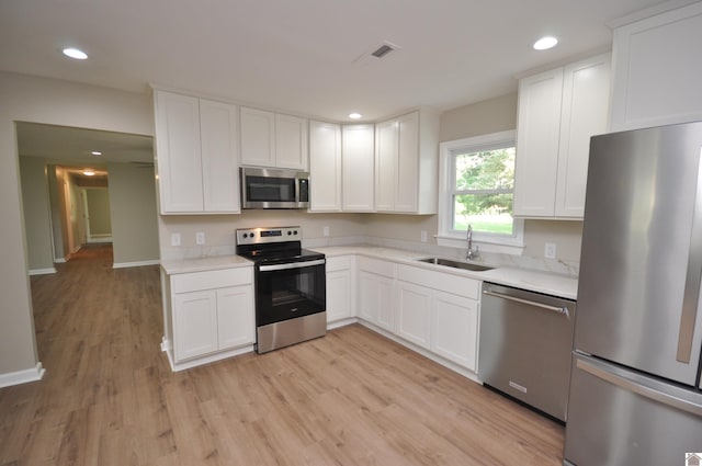 kitchen featuring sink, light hardwood / wood-style flooring, stainless steel appliances, and white cabinets