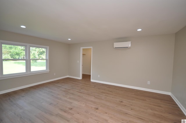 empty room with a wall mounted air conditioner and light wood-type flooring