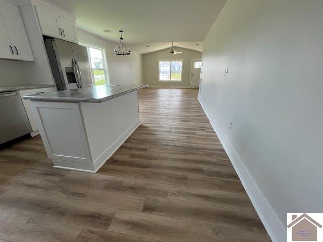 kitchen featuring appliances with stainless steel finishes, white cabinetry, a kitchen island, vaulted ceiling, and hardwood / wood-style flooring