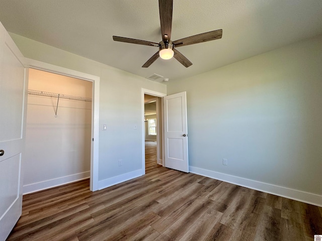 unfurnished bedroom featuring ceiling fan, hardwood / wood-style flooring, and a closet