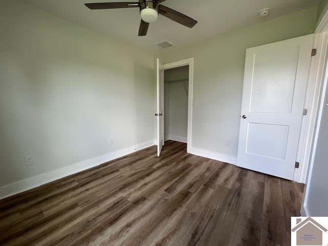 unfurnished bedroom featuring ceiling fan, a closet, and dark wood-type flooring