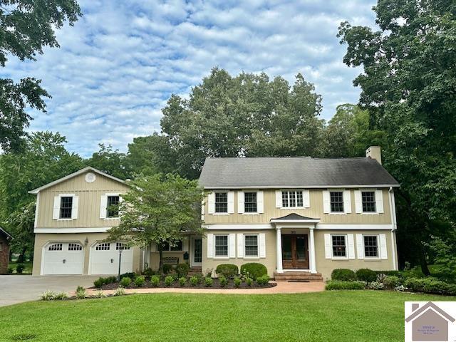 view of front of home with a garage, a chimney, concrete driveway, and a front yard