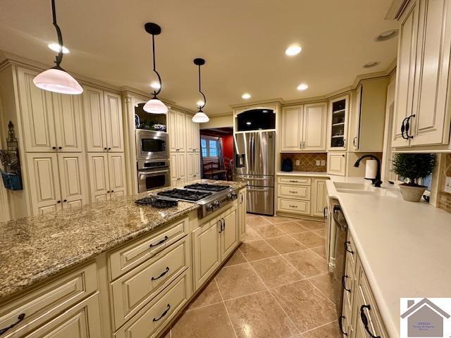 kitchen with stainless steel appliances, pendant lighting, glass insert cabinets, and a sink