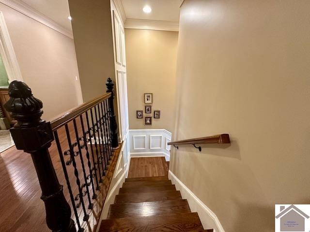 stairs featuring dark wood-type flooring and ornamental molding