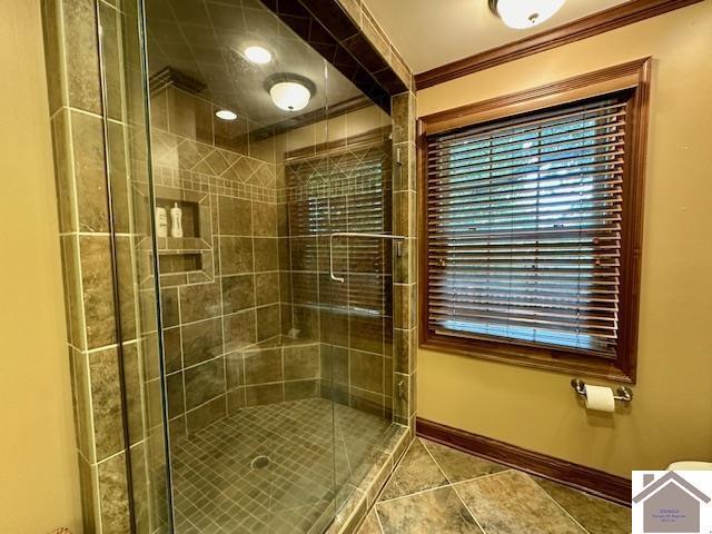 bathroom featuring crown molding, tile patterned floors, a shower stall, and baseboards