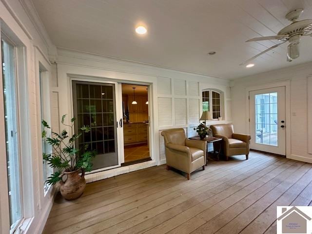 living area featuring hardwood / wood-style flooring, crown molding, and ceiling fan