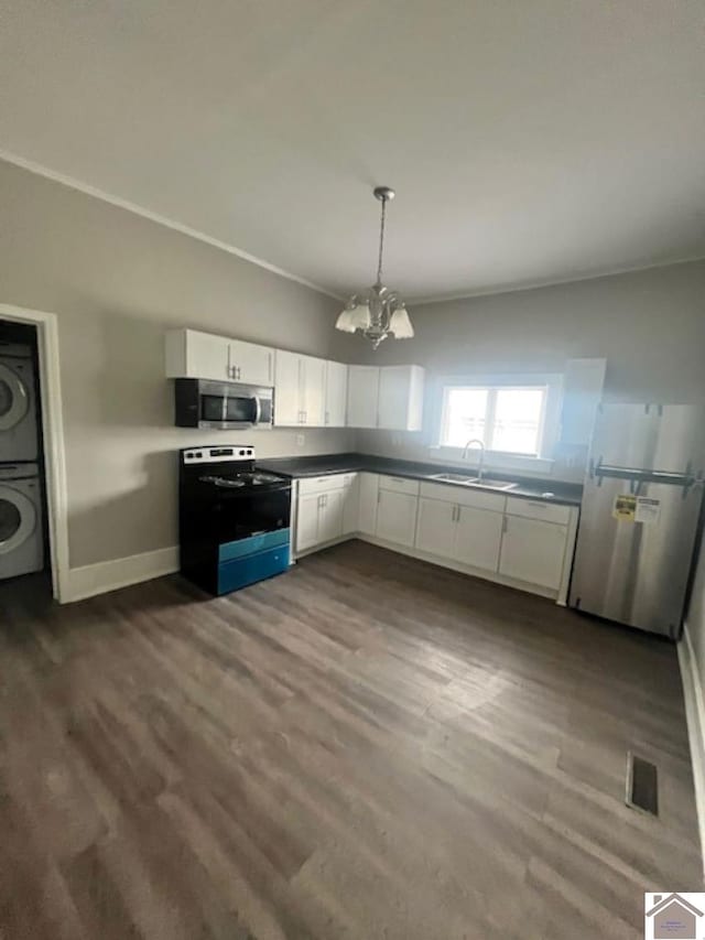 kitchen with stacked washer / drying machine, sink, white cabinetry, hanging light fixtures, and stainless steel appliances