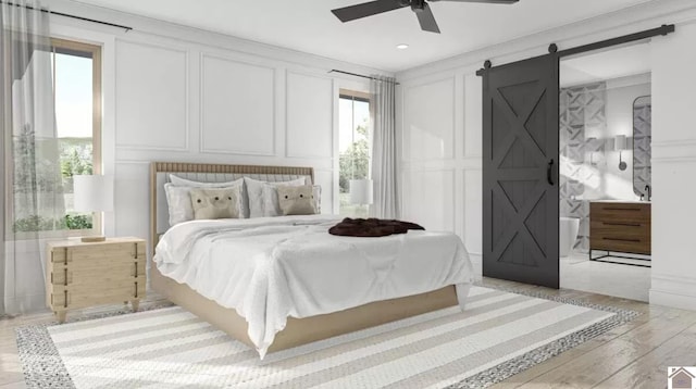 bedroom featuring light hardwood / wood-style floors, a barn door, and ceiling fan