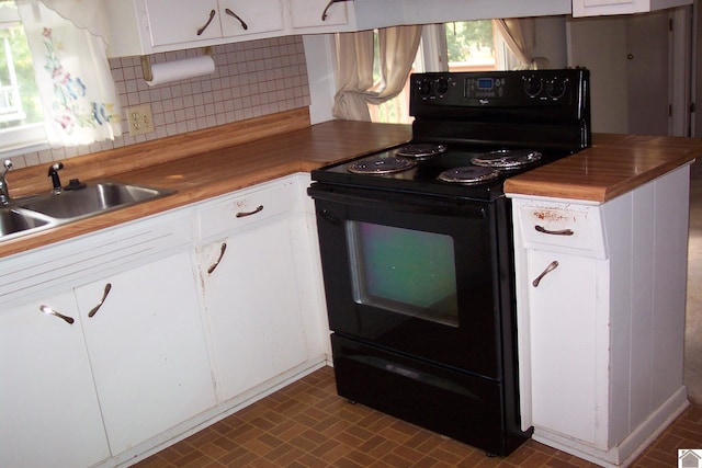 kitchen with sink, white cabinets, wood counters, and black / electric stove