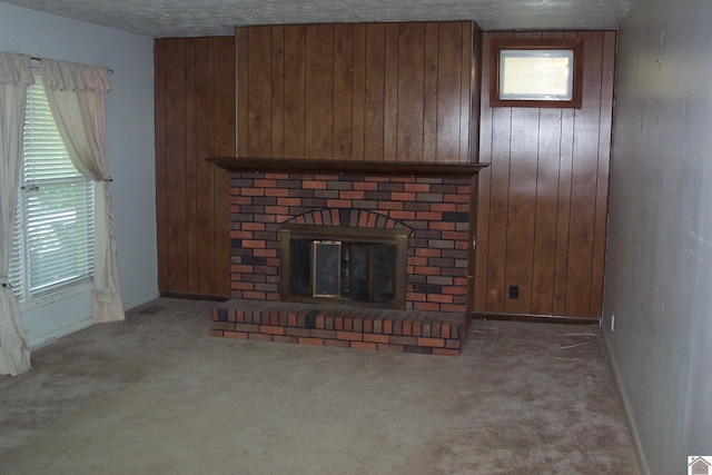 unfurnished living room featuring plenty of natural light, carpet floors, wooden walls, and a brick fireplace