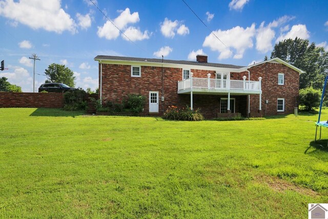 back of property featuring a balcony and a lawn