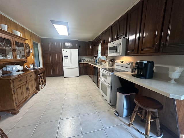 kitchen with a breakfast bar area, crown molding, white appliances, and light tile patterned floors