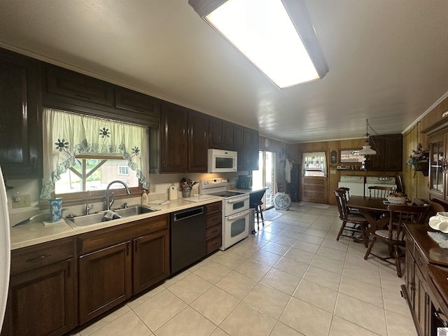 kitchen with sink, white appliances, a healthy amount of sunlight, and light tile patterned flooring