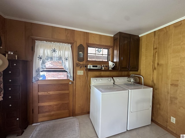 laundry area with light tile patterned floors, washing machine and dryer, cabinets, and wood walls