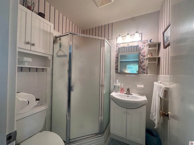 bathroom featuring vanity, tile walls, a shower with shower door, toilet, and backsplash