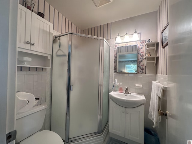 bathroom with vanity, toilet, tile walls, and walk in shower