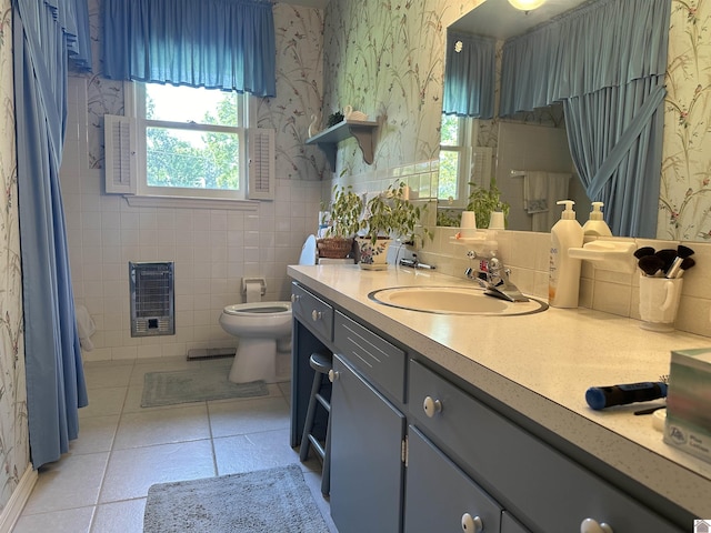 bathroom with heating unit, tile walls, tile patterned flooring, vanity, and toilet