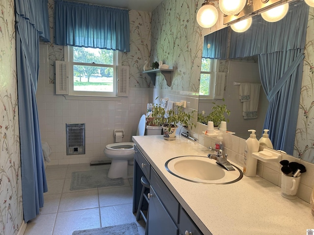 bathroom with heating unit, tile walls, tile patterned flooring, vanity, and toilet