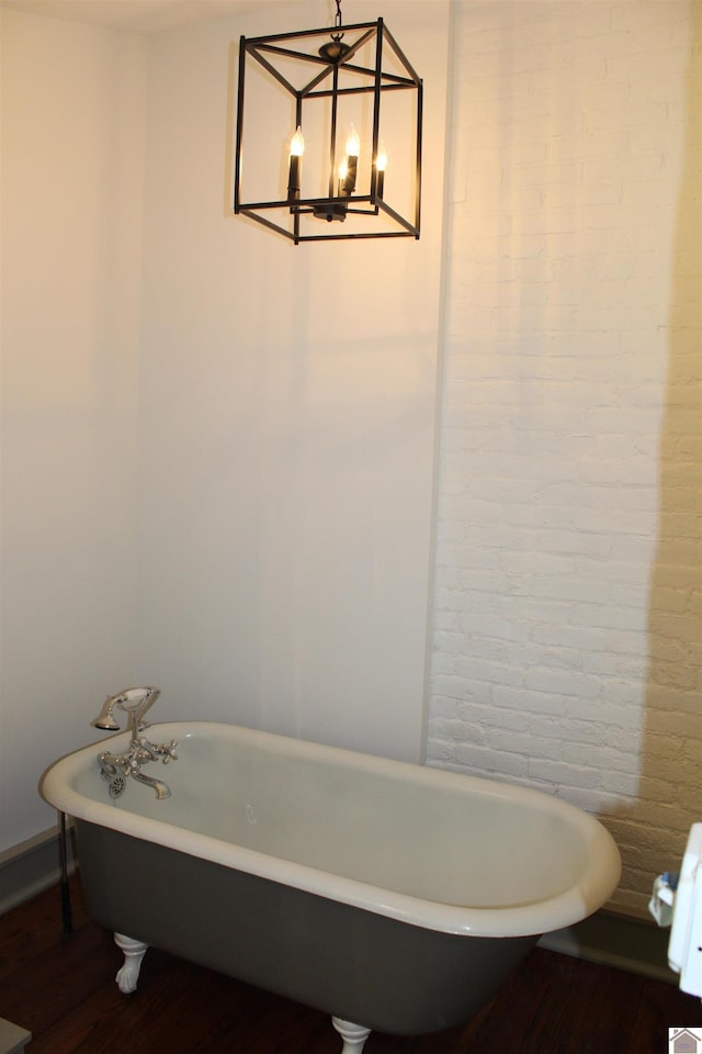 bathroom featuring a notable chandelier, wood-type flooring, and a washtub