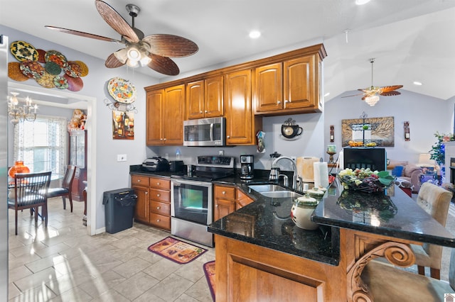 kitchen featuring ceiling fan with notable chandelier, appliances with stainless steel finishes, lofted ceiling, light tile patterned floors, and sink