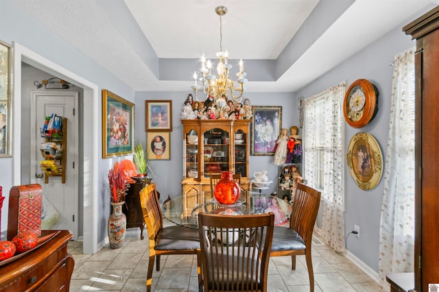 dining space featuring a notable chandelier, light tile patterned floors, and a tray ceiling