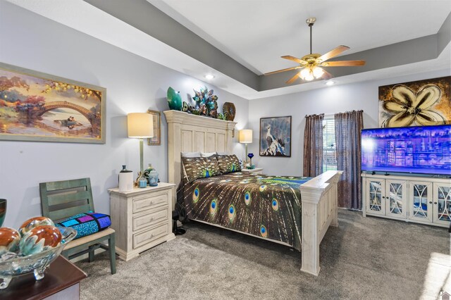 carpeted bedroom featuring ceiling fan and a raised ceiling