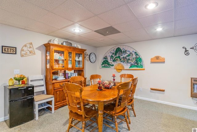 carpeted dining space featuring a drop ceiling