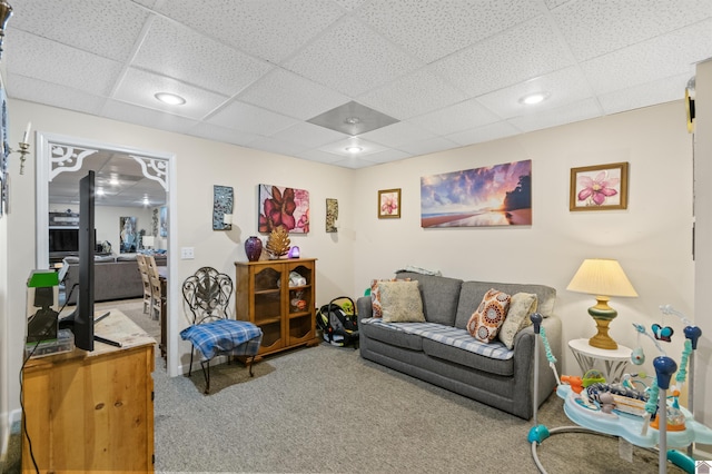 carpeted living room featuring a drop ceiling