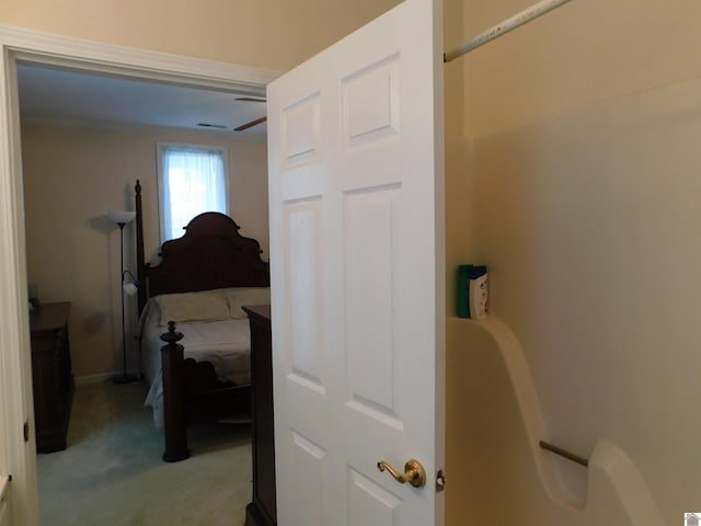 bedroom with ornamental molding and light colored carpet