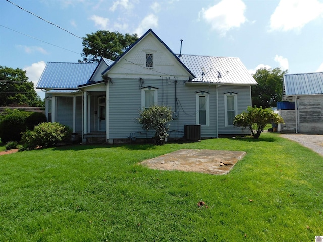 back of property with central AC and a lawn