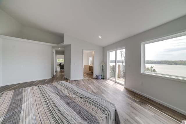 unfurnished bedroom with lofted ceiling, ensuite bath, a water view, hardwood / wood-style floors, and access to exterior