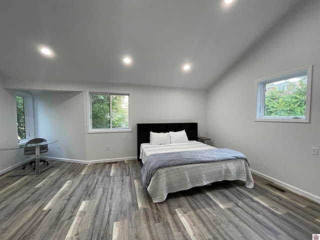 bedroom featuring hardwood / wood-style floors, vaulted ceiling, and multiple windows