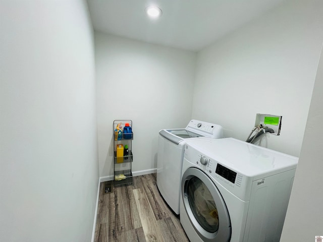 laundry area with independent washer and dryer and light hardwood / wood-style flooring