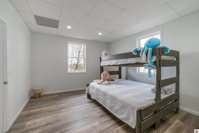 bedroom featuring a paneled ceiling, multiple windows, and hardwood / wood-style floors