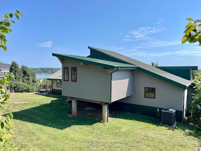 view of side of property with a water view, a lawn, and central air condition unit