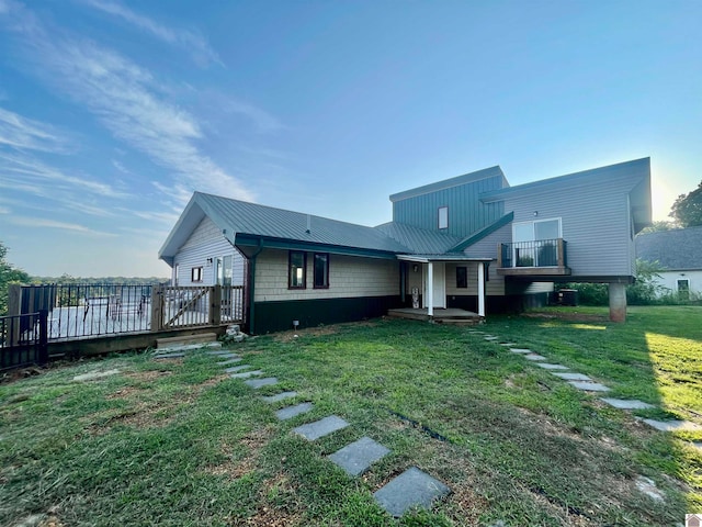 back of property featuring a wooden deck and a lawn