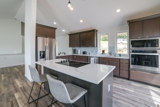 kitchen featuring decorative backsplash, light hardwood / wood-style flooring, appliances with stainless steel finishes, dark brown cabinets, and sink