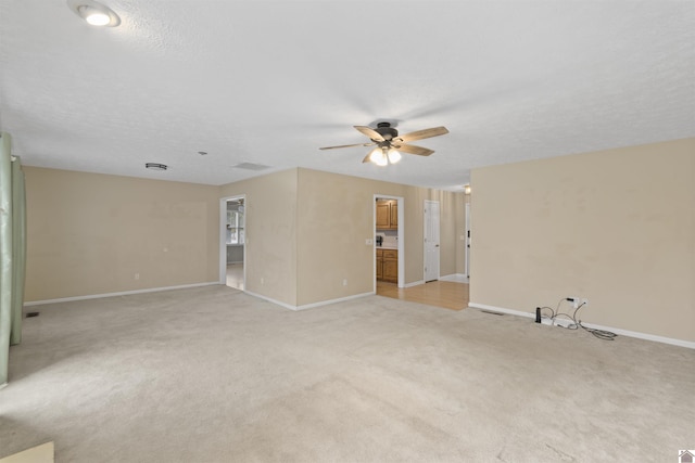 empty room featuring ceiling fan, light carpet, and a textured ceiling