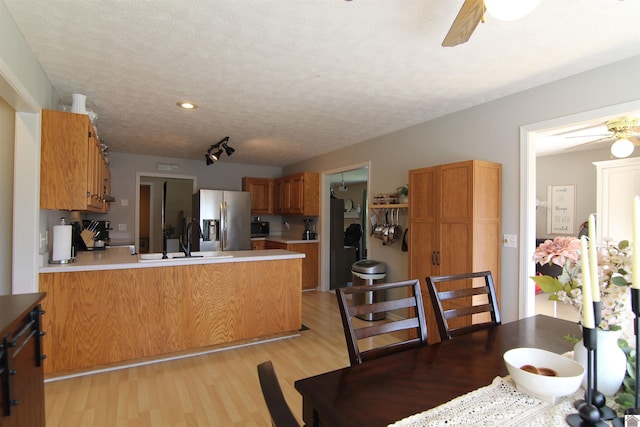 kitchen featuring stainless steel refrigerator with ice dispenser, light wood-type flooring, ceiling fan, sink, and kitchen peninsula