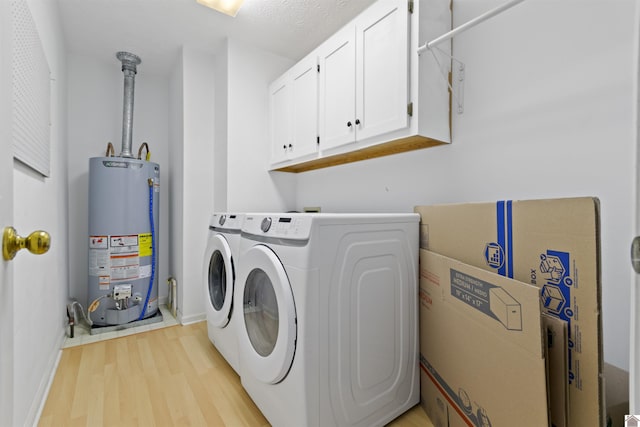 laundry area with light hardwood / wood-style flooring, gas water heater, cabinets, and washing machine and clothes dryer