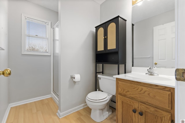 bathroom with vanity, hardwood / wood-style flooring, a shower with shower door, and toilet