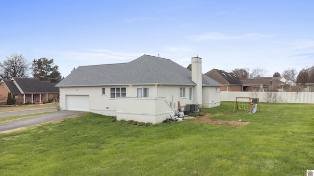 back of property with a garage, a lawn, and central air condition unit