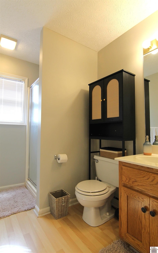 bathroom with a textured ceiling, hardwood / wood-style floors, toilet, an enclosed shower, and vanity