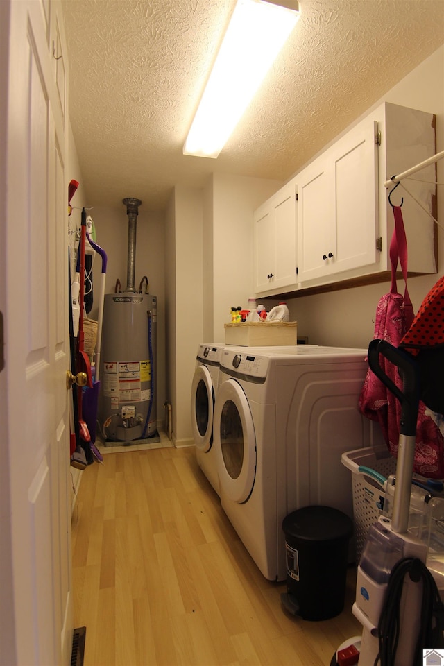 laundry room featuring light hardwood / wood-style flooring, a textured ceiling, cabinets, gas water heater, and separate washer and dryer